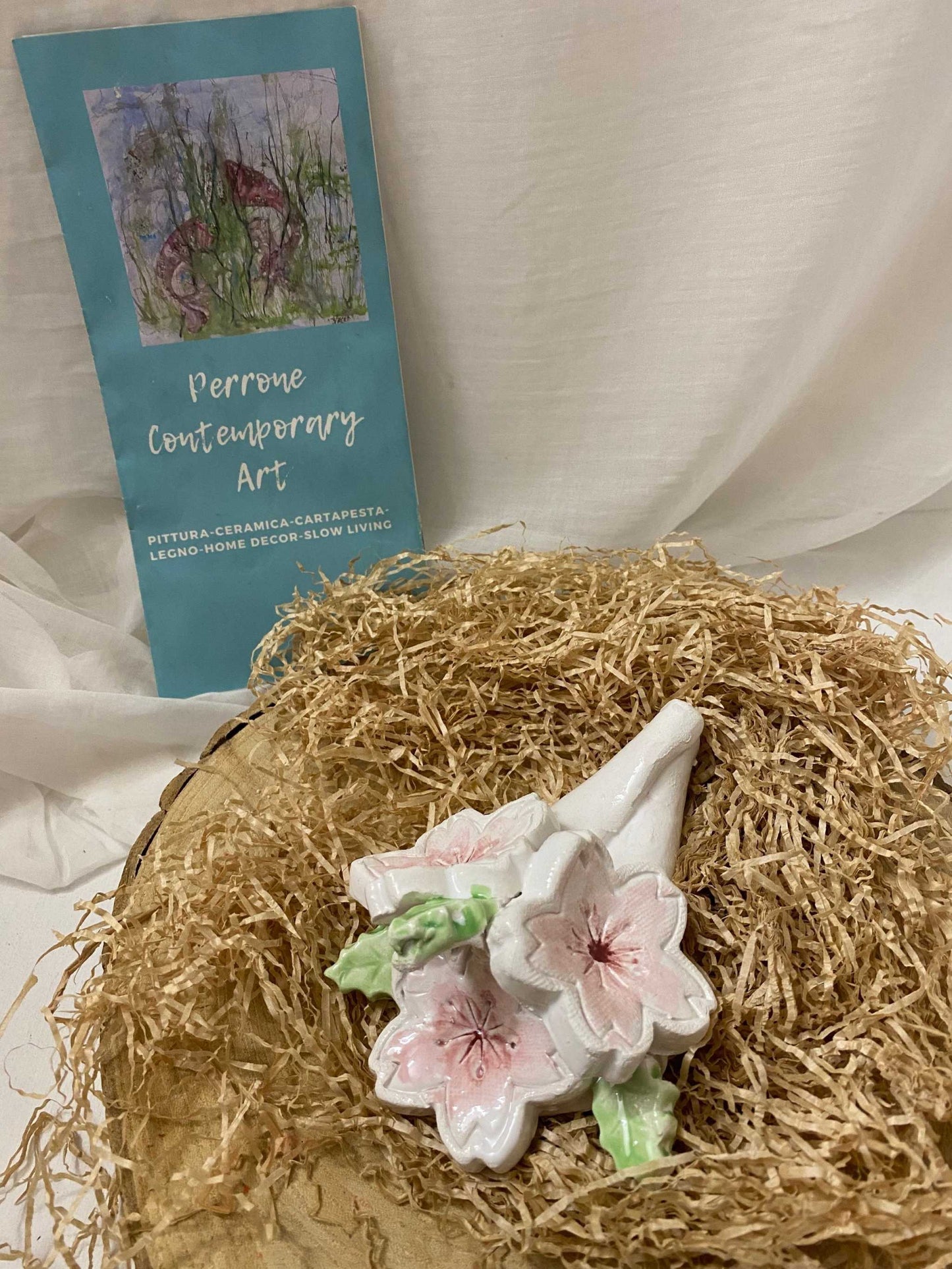 Small 12 cm white ceramic decoration with pink cherry blossom design from Ciliegio Collection placed on straw bedding