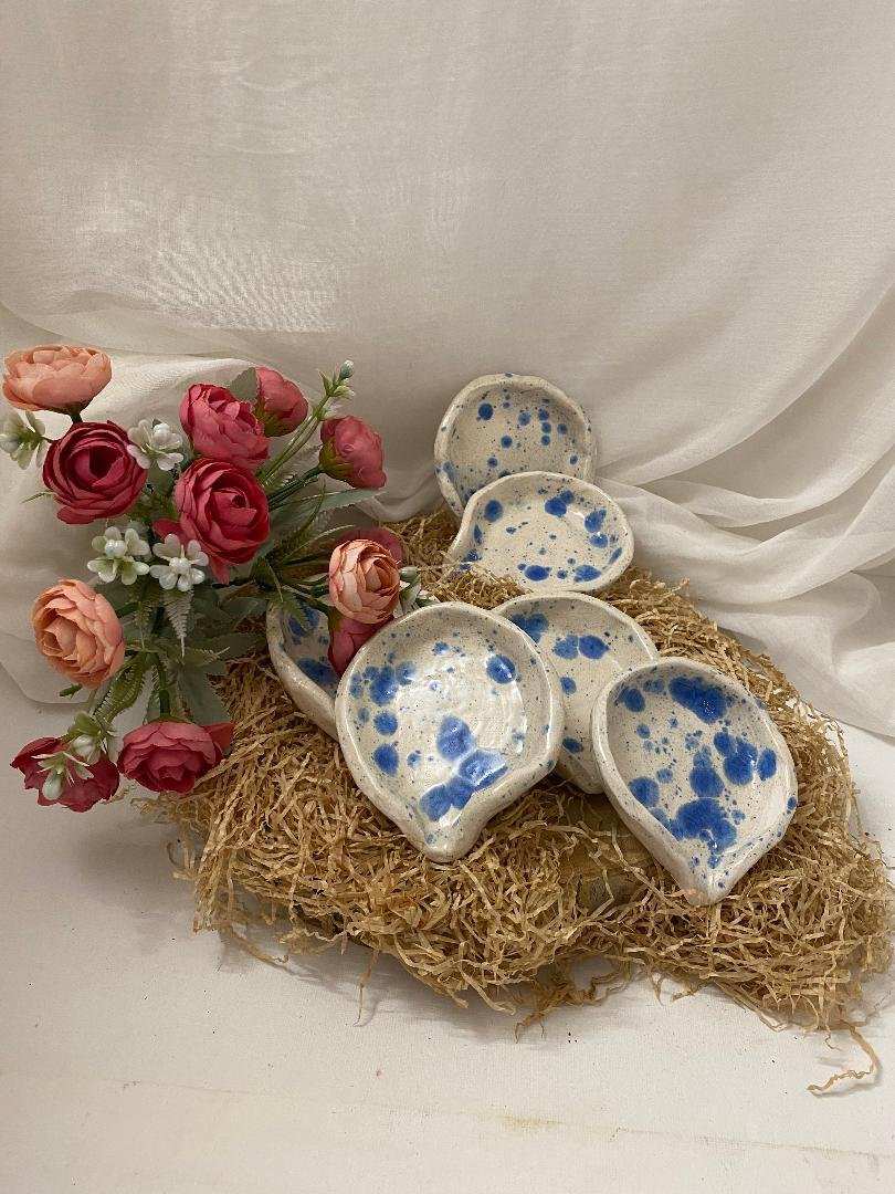 Set of six handmade white ceramic spoon rests with blue spots, elegant and functional table accessories from the Summer Collection.