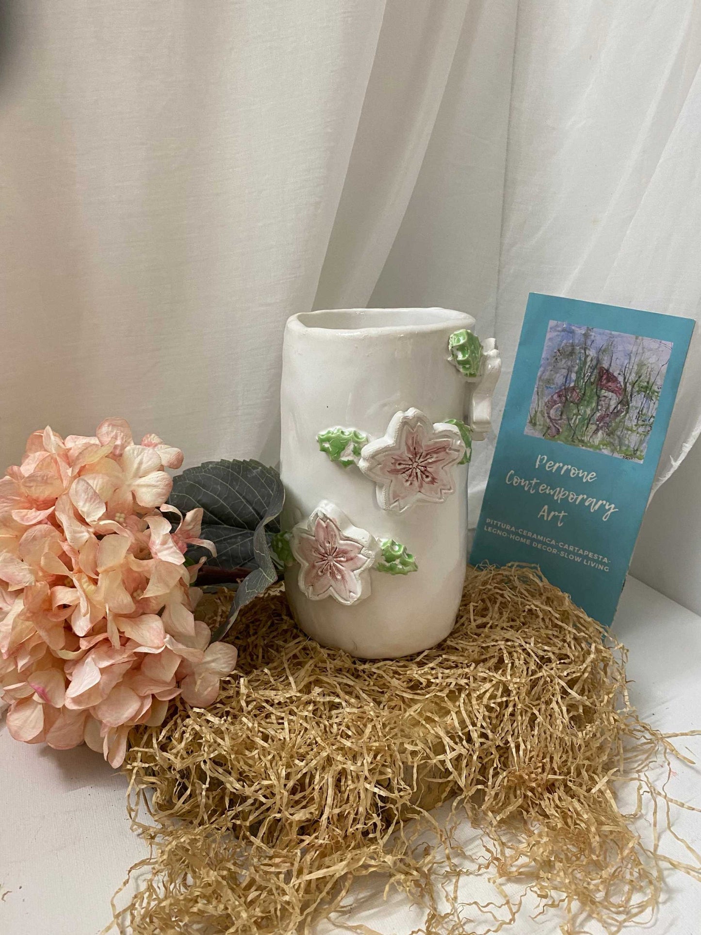 White ceramic Portamestoli Collezione Ciliegio utensil holder with floral design on straw and decorative backdrop