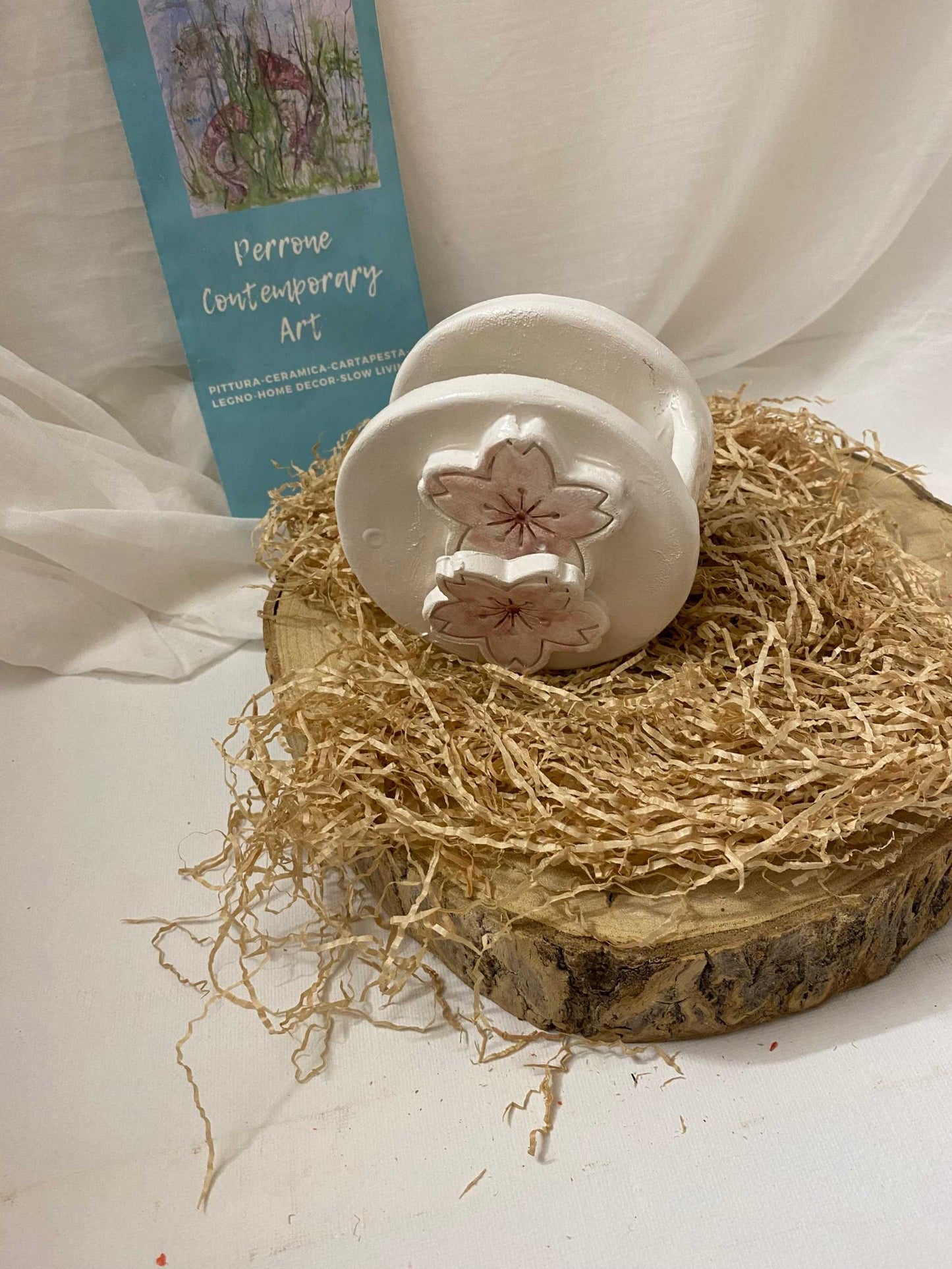 Small white ceramic Vaso Aesthetic Circle vase with floral decorations from Ciliegio Collection on natural wood and straw background