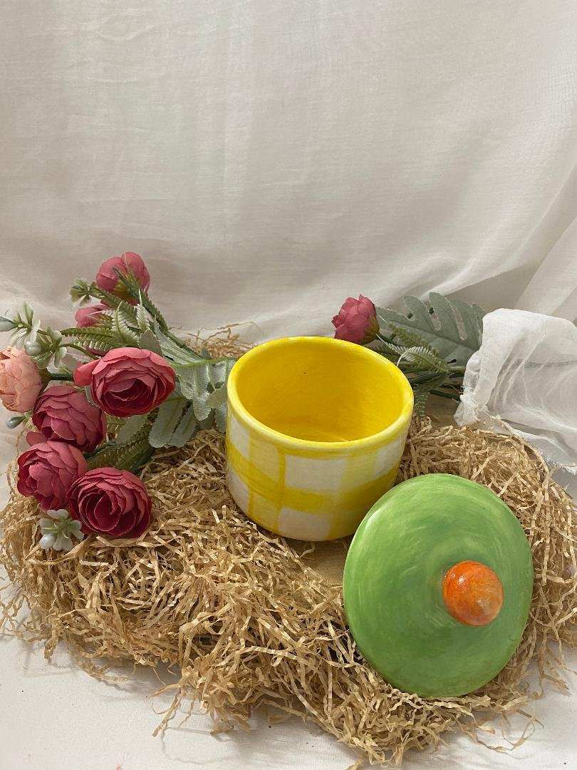 white ceramic sugar bowl with yellow checkered pattern and green lid with orange knob from Fruit collection on straw with pink flowers