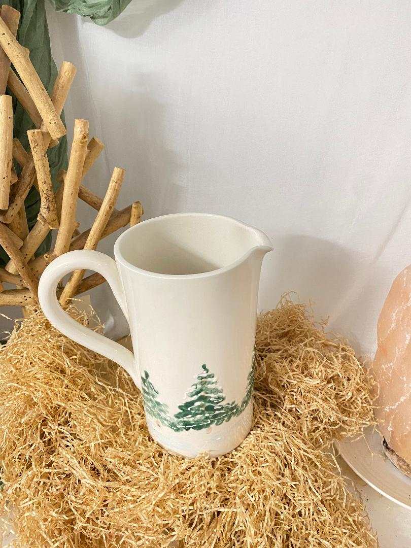 Handcrafted ceramic pitcher with winter-themed green tree painting, rustic and elegant for seasonal table decor