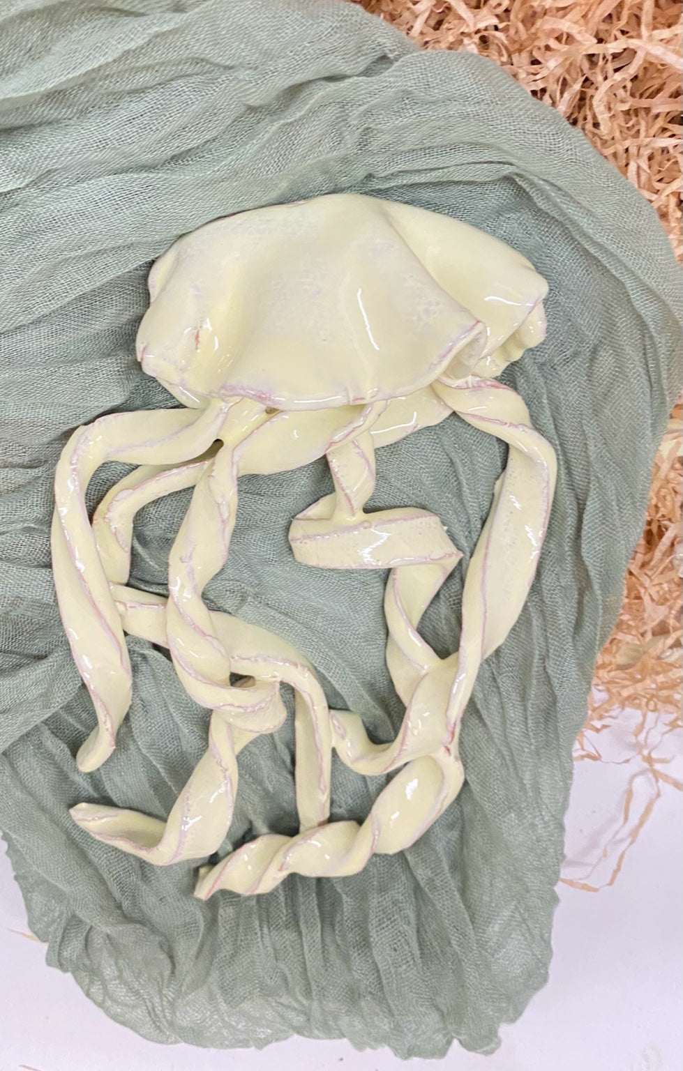 Handmade glazed ceramic jellyfish sculpture in pearly ivory with pink details, inspired by Salento sea life, part of the Mediterraneo collection.