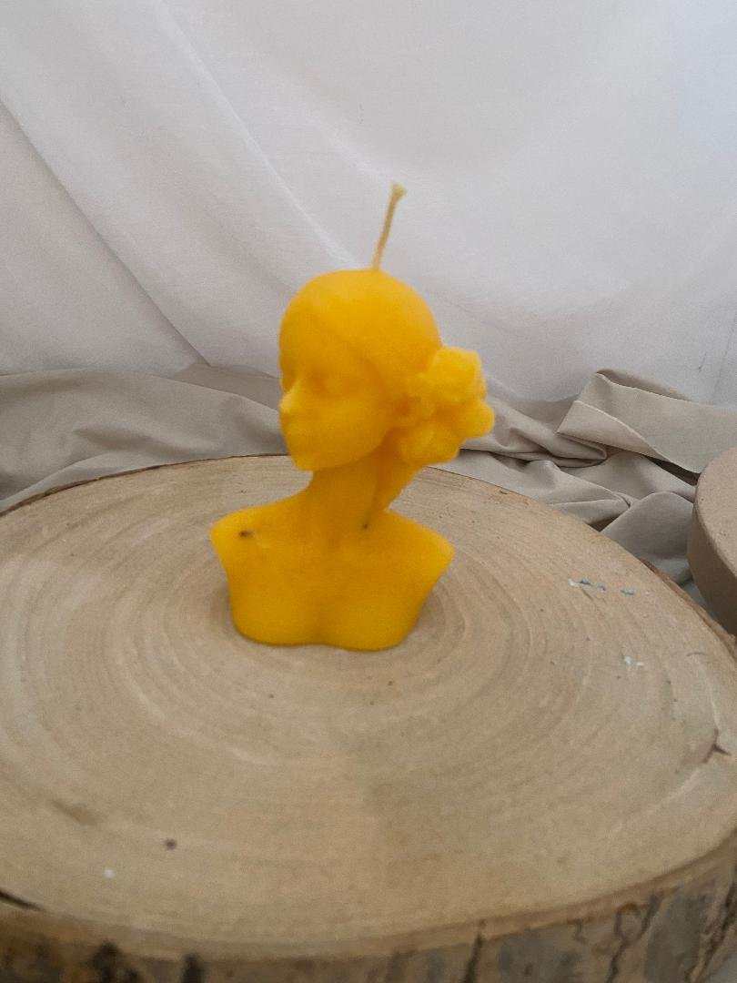Handcrafted "Candela Miss" beeswax candle in golden honey color shaped as a feminine bust with flower detail, natural and elegant decor.