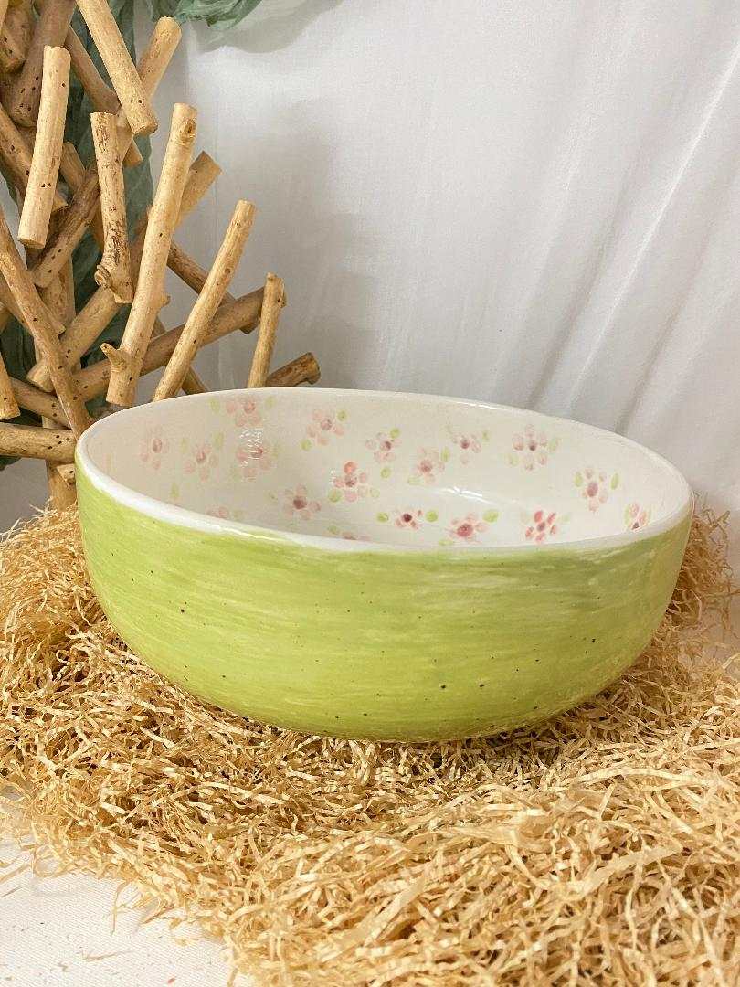 White ceramic salad bowl with green exterior and floral interior design from Primavera collection on natural straw base