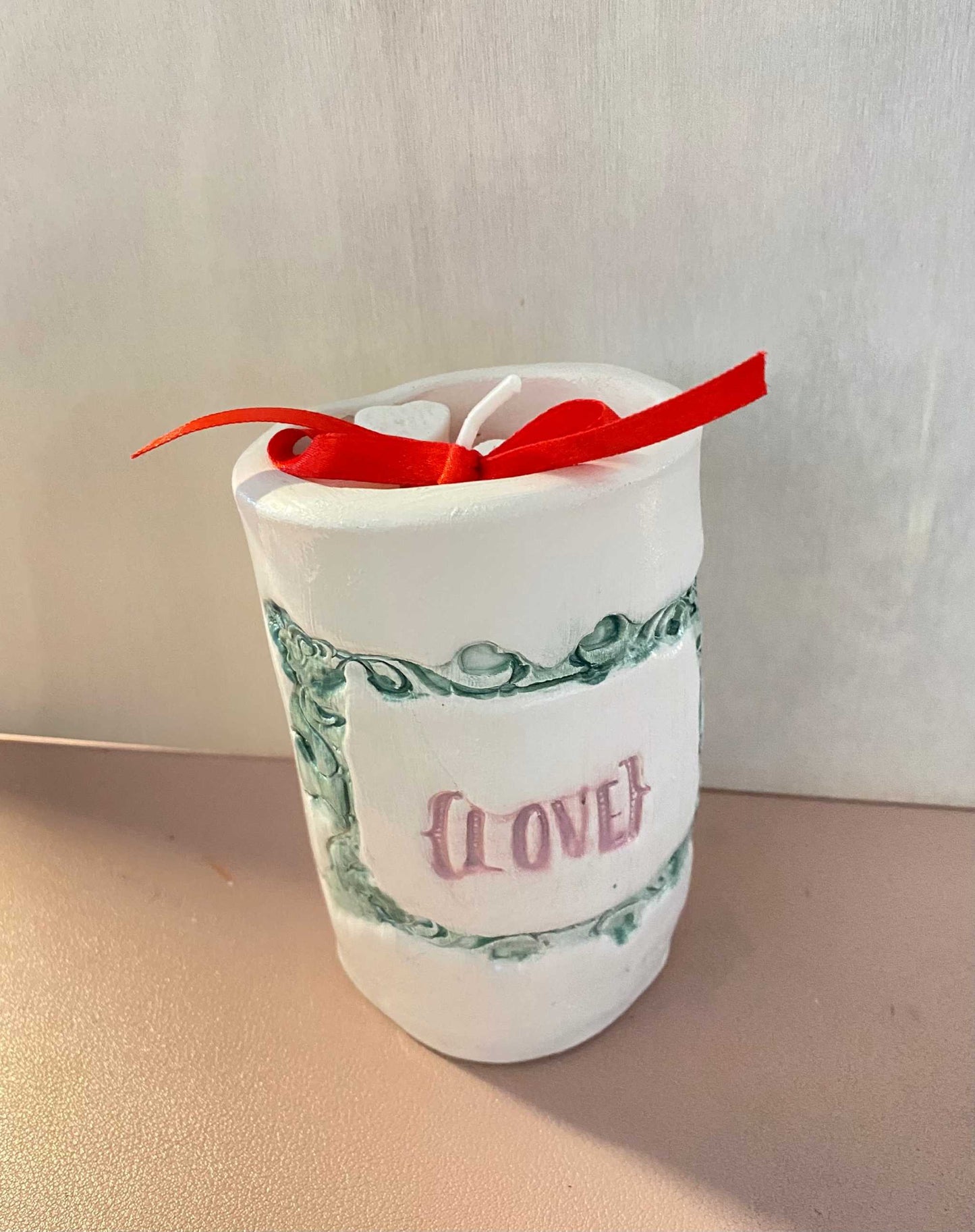 Ceramic jar candle from Gocce del Salento collection with decorative design and red ribbon.
