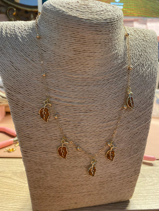 Gold stainless steel leaf necklace from Luxury Bijioux collection displayed on a woven bust
