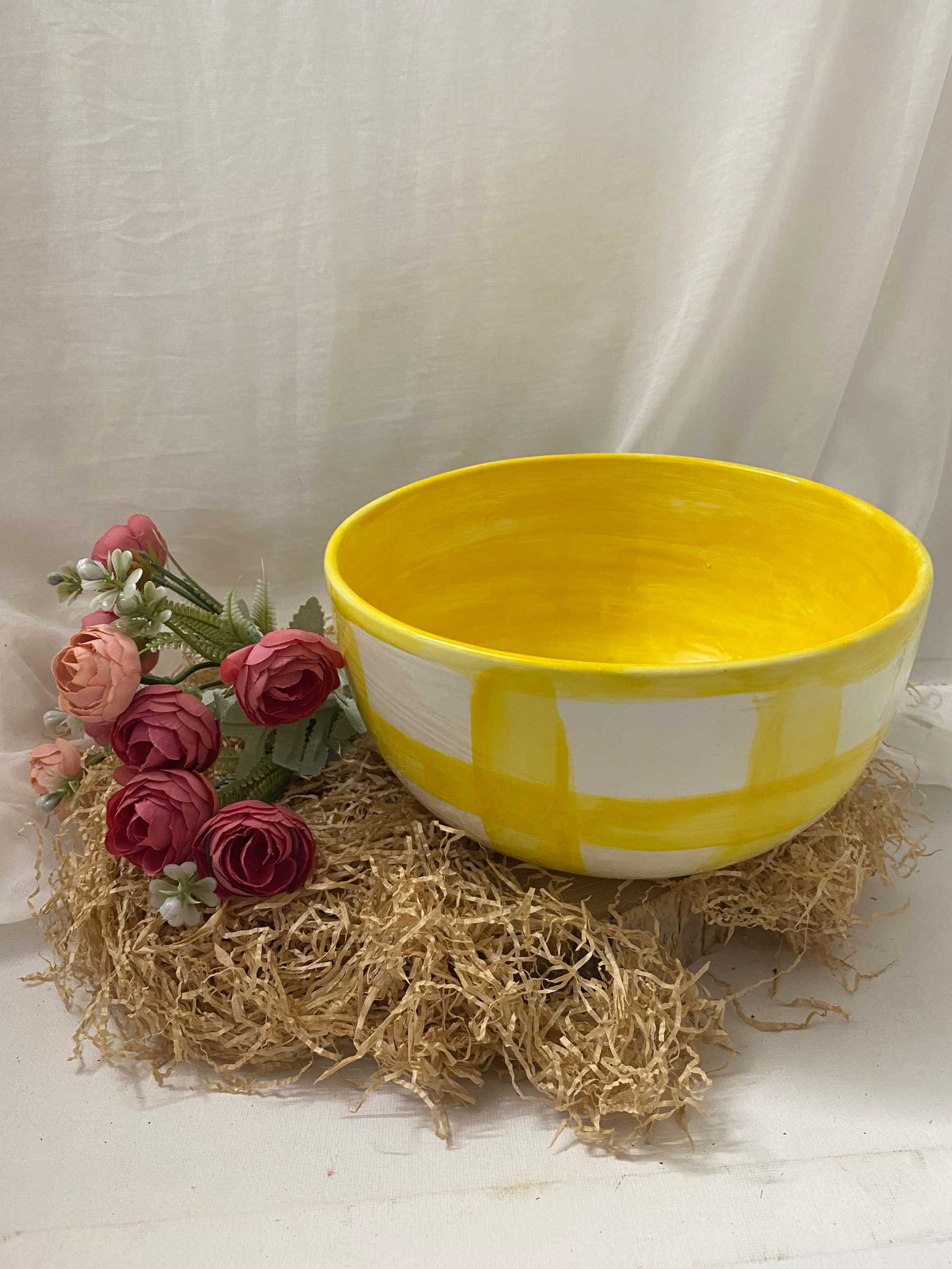 Bright yellow and white checkered Coppa Insalatiera bowl from Fruit Collection on natural straw with pink flowers