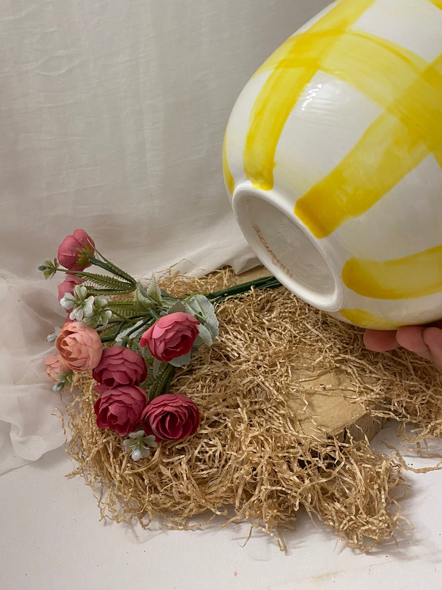 Bright yellow and white Coppa Insalatiera bowl from the Fruit collection placed near decorative pink flowers and straw mat.