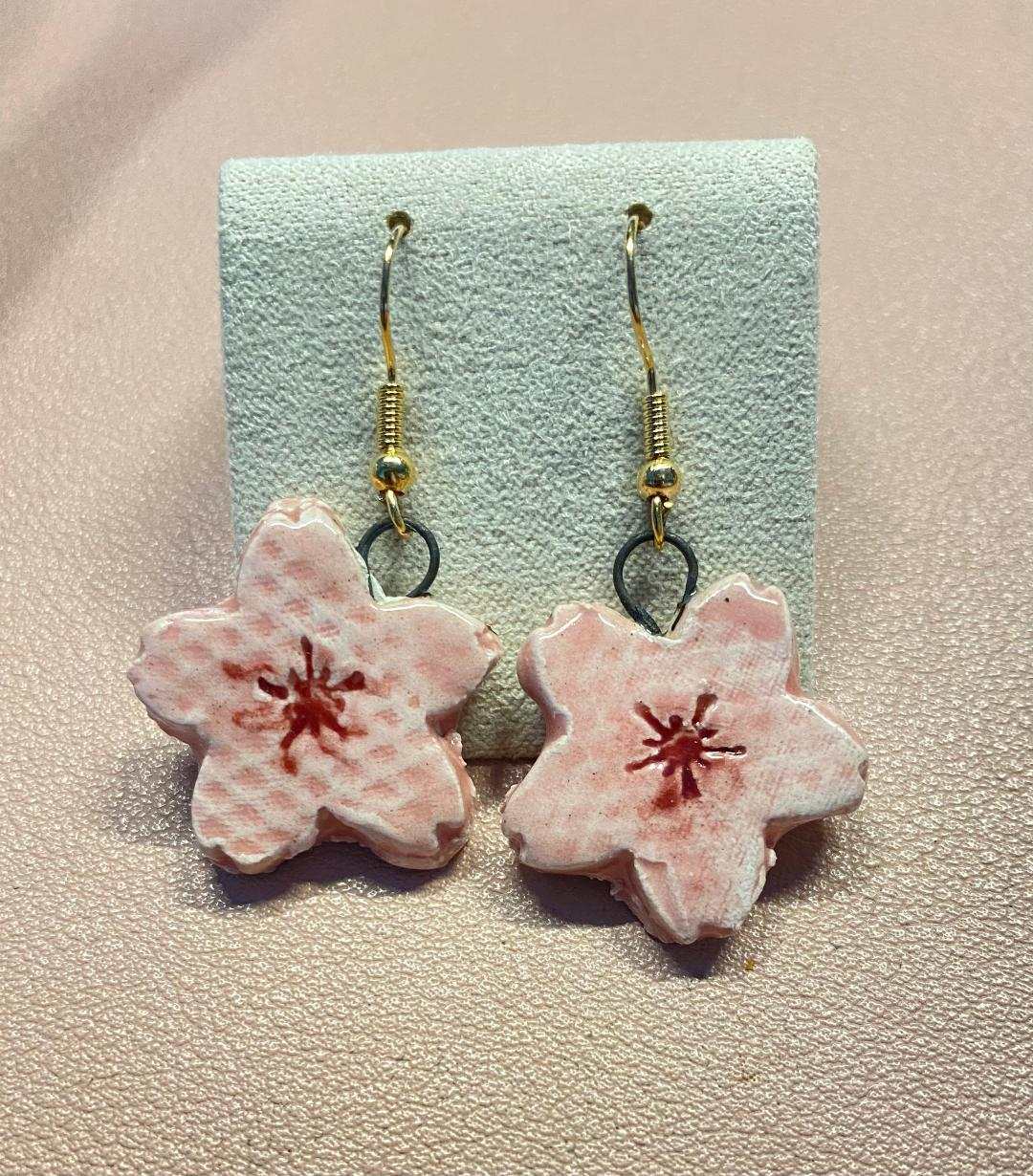 Handmade pink cherry blossom ceramic earrings with gold-tone hooks, delicate floral design inspired by Sakura flowers.
