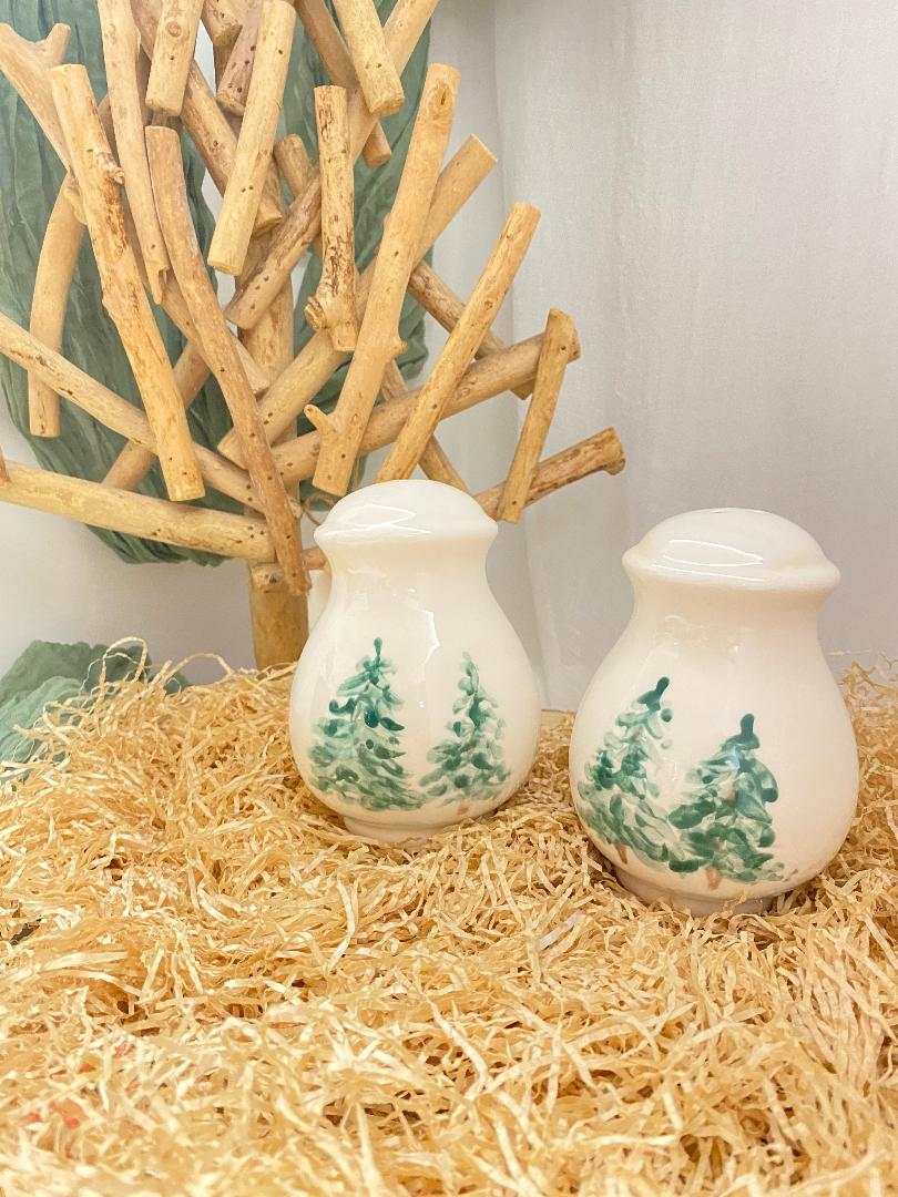 white ceramic salt and pepper shakers with green winter tree design from Collezione Inverno on straw background